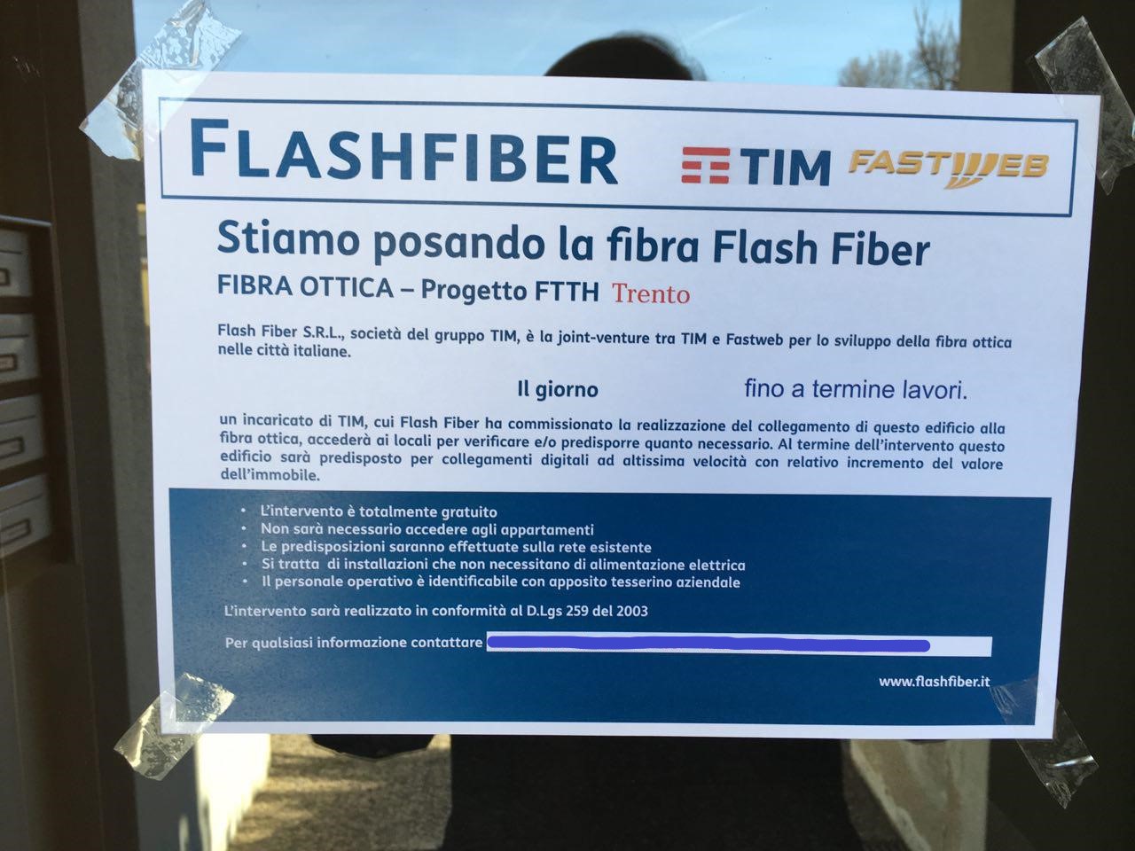 Foglio di carta appeso con il logo Flash Fiber, che dice "stiamo posando la fibra ottica"