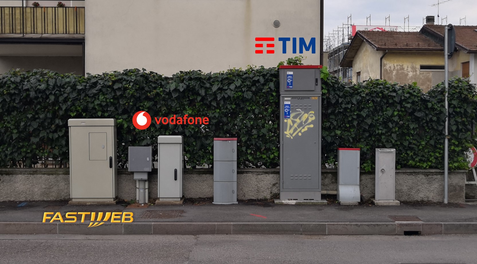 Strada con marciapiede, sul quale sono posizionati in fila alcuni armadi o box per la FTTC